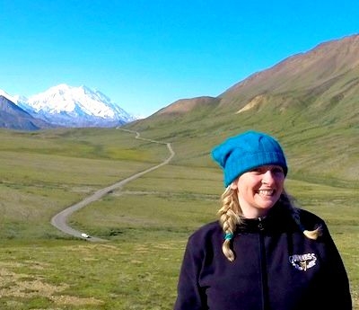 Kirsten Thompson stood in front of tundra with Mount Denali in the background in Denali National Park Alaska, USA.